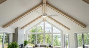 A minimalist indoor-outdoor ceiling fan with light fixture mounted on a high vaulted ceiling inside a home.