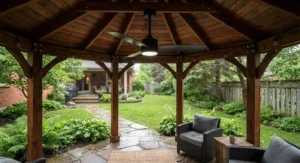 Black wet rated ceiling fan securely mounted in a backyard wooden gazebo, designed to withstand rain and outdoor moisture.