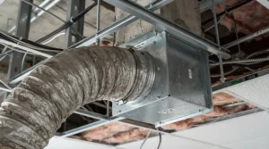 Connecting a 4-inch duct securely to a ceiling-mounted bathroom exhaust fan during setup.
